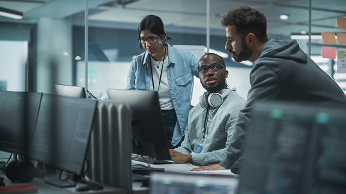 three people looking a computer monitor